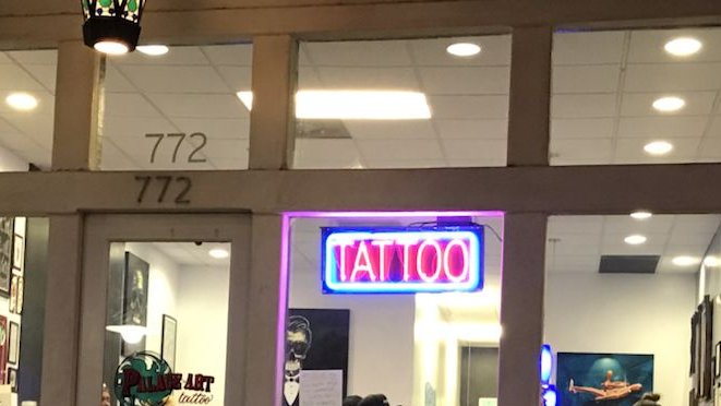 The shop front at 772 E Thousand Oaks Blvd at night, a neon TATTOO sign in the window