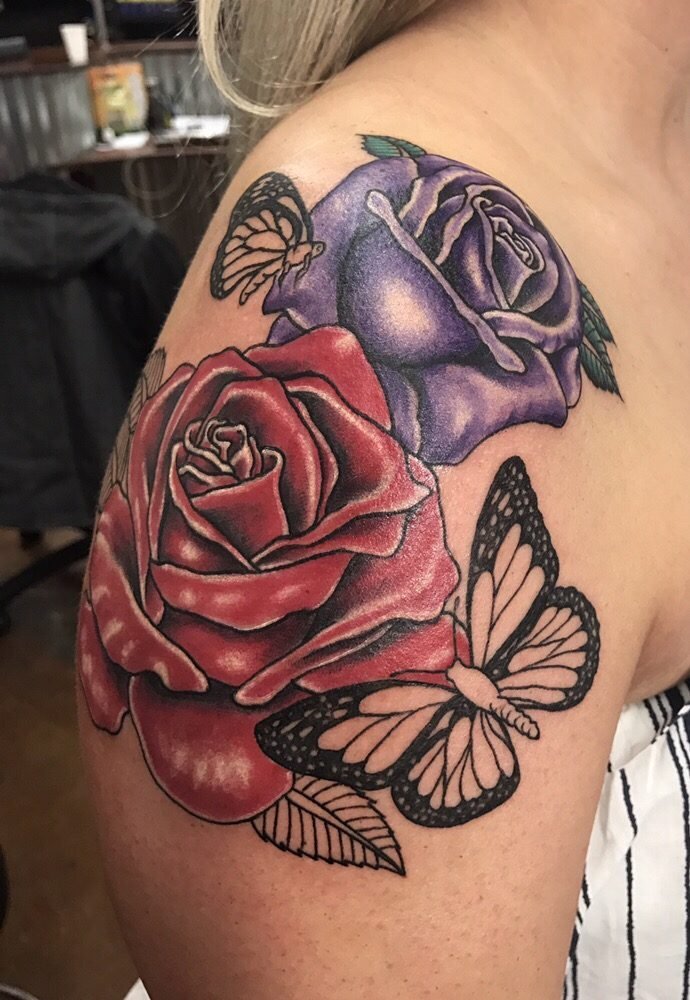 A red and a purple rose with two black-and-white butterflies on a shoulder