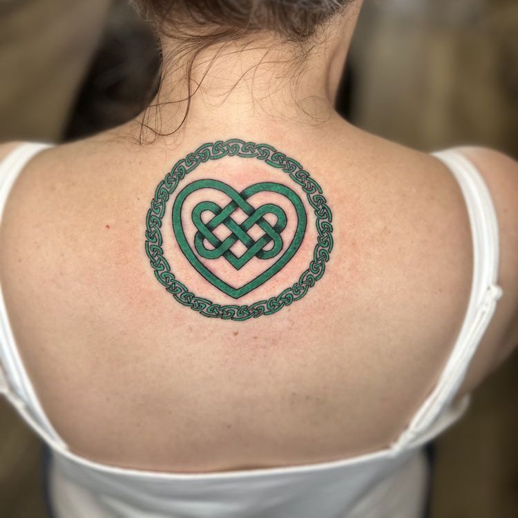 A green Celtic knot heart inside a braided ring across the upper back